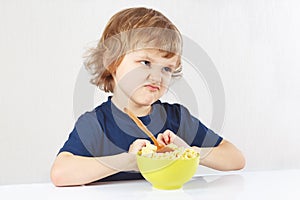 Little cute blonde boy refuses to eat porridge