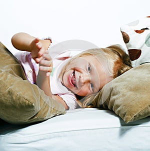 Little cute blonde norwegian girl playing on sofa with pillows,
