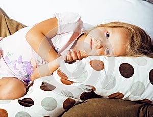 Little cute blonde norwegian girl playing on sofa with pillows,