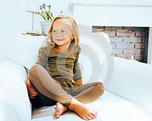 Little cute blonde norwegian girl playing on sofa with pillows, crazy home alone, lifestyle people concept