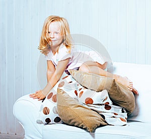 Little cute blonde norwegian girl playing on sofa with pillows, crazy home alone, lifestyle people concept