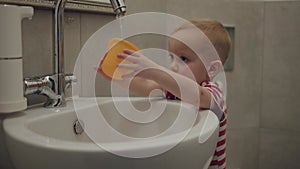 Little cute boy in bathroom joyful playing with stream of water from faucet. Stream of water in bathroom boy splashes