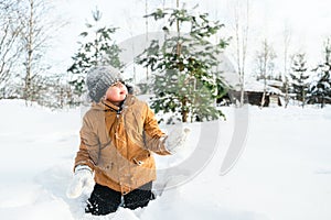 Little cute boy in black hat,orange jacket is lying,playing in snow. Kid walking in beautiful frozen forest,park among