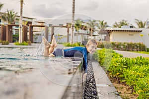 Little cute boy in blue water of the swimming pool, summer time for fun