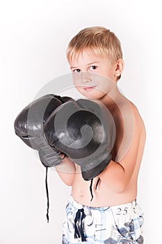 Little cute boy with boxing gloves celebrating his victory on the blank wall background