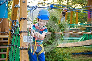 Little cute boy enjoying activity in a climbing adventure park o