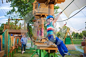 Little cute boy enjoying activity in a climbing adventure park o