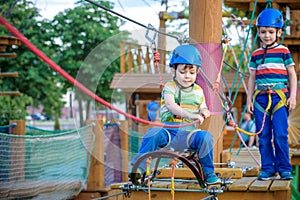 Little cute boy enjoying activity in a climbing adventure park on a summer sunny day. toddler climbing in a rope playground