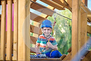 Little cute boy enjoying activity in a climbing adventure park on a summer sunny day. toddler climbing in a rope playground