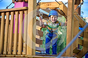 Little cute boy enjoying activity in a climbing adventure park on a summer sunny day. toddler climbing in a rope playground