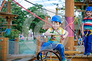 Little cute boy enjoying activity in a climbing adventure park on a summer sunny day. toddler climbing in a rope playground struct