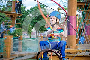 Little cute boy enjoying activity in a climbing adventure park on a summer sunny day. toddler climbing in a rope playground struct