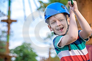 Little cute boy enjoying activity in a climbing adventure park on a summer sunny day. toddler climbing in a rope playground struct