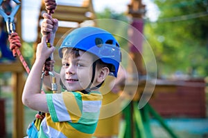 Little cute boy enjoying activity in a climbing adventure park on a summer sunny day. toddler climbing in a rope playground struct