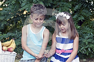 Little cute boy and girl sit in the grass and play