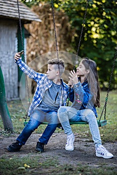 Little cute boy and girl are taking picture of themselves for selfie with phone