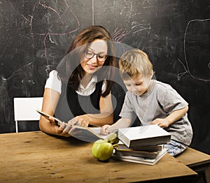 Little cute boy in glasses with young real teacher, classroom studying