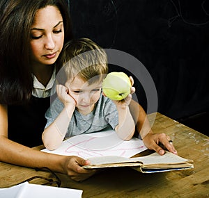 Little cute boy in glasses with young real teacher, classroom studying, lifestyle people concept