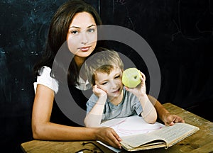 little cute boy in glasses with young real teacher, classroom studying, lifestyle people concept
