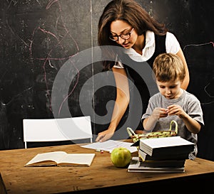 Little cute boy in glasses with young real teacher, classroom studying