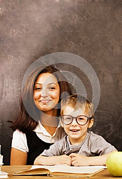 Little cute boy with young teacher in classroom studying