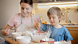 Little cute boy helping his mother mixing dough for pie or cake. Children cooking with parents, little chef, family