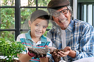 Little cute boy and his grandfather holding dry ground in their hands on greenhouse.Happy smile grandfather teaching his