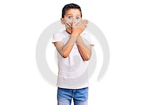 Little cute boy kid wearing casual white tshirt shocked covering mouth with hands for mistake