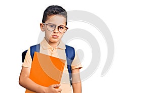 Little cute boy kid wearing school bag and holding book thinking attitude and sober expression looking self confident