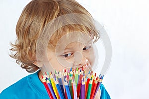 Little cute boy looks on color pencils