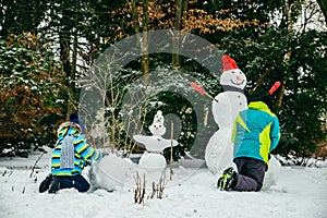 little cute boy making snowman. rolling big snowball