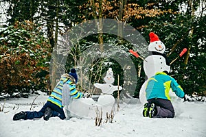 little cute boy making snowman. rolling big snowball