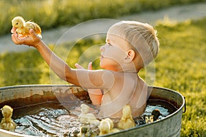 Little cute boy play with duckling in the hands on a bright back