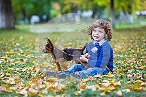 Little cute boy playing with his dog in autumn park