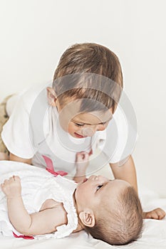 Little Cute Boy Playing with His Infant Sister and Smiling.Against White Background