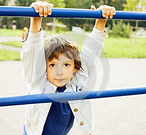 Little cute boy playing on playground, hanging on gymnastic ring