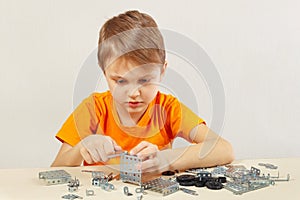 Little cute boy plays with mechanical constructor at table