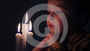 little cute boy prays in front of a burning candle. Child's prayer