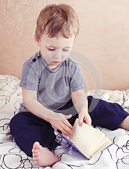 Little cute boy reading book in bed at home, lifestyle poeple during corona virus isolation