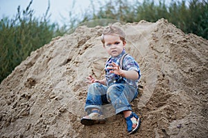 Little cute boy riding a roller coaster of sand on the bottom. Memories childhood and carefree