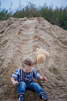 Little cute boy riding a roller coaster of sand on the bottom. Memories childhood and carefree