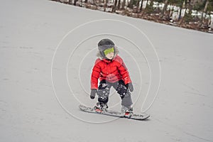 Little cute boy snowboarding. Activities for children in winter. Children`s winter sport. Lifestyle