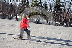 Little cute boy snowboarding. Activities for children in winter. Children`s winter sport. Lifestyle