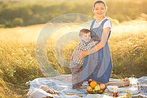 Little cute boy son and his beautiful pregnant mom at picnic