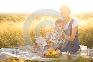 Little cute boy son and his beautiful pregnant mom at picnic