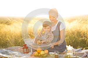 Little cute boy son and his beautiful pregnant mom at picnic