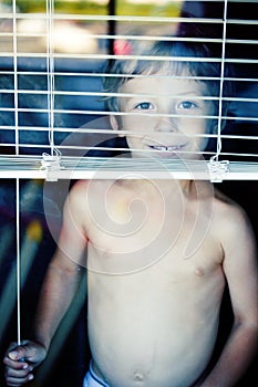 Little cute boy throught window making funny faces, home alone lifestyle concept