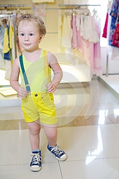 Little cute boy in yellow poses in store with