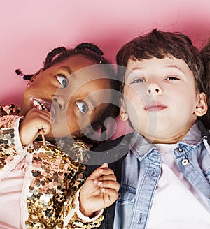 Little cute caucasian boy and african american girl hugging playing on pink background, happy smiling diverse nation and