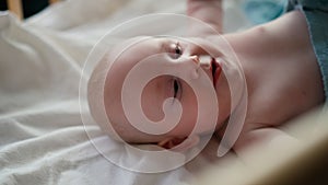 Little cute causian baby boy, smiling at camera, the boy lies on his back and turns